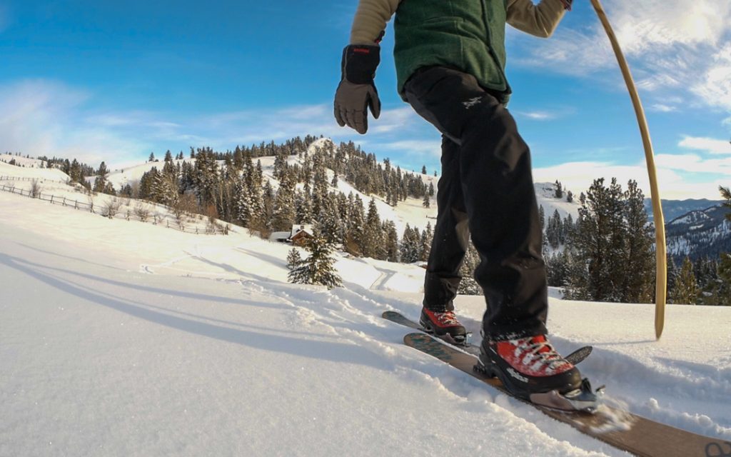 Alpina Alaska 75mm (3 pin) boots A bluebird sunny day showing a person skiing down a hill wearing the Alpina boots